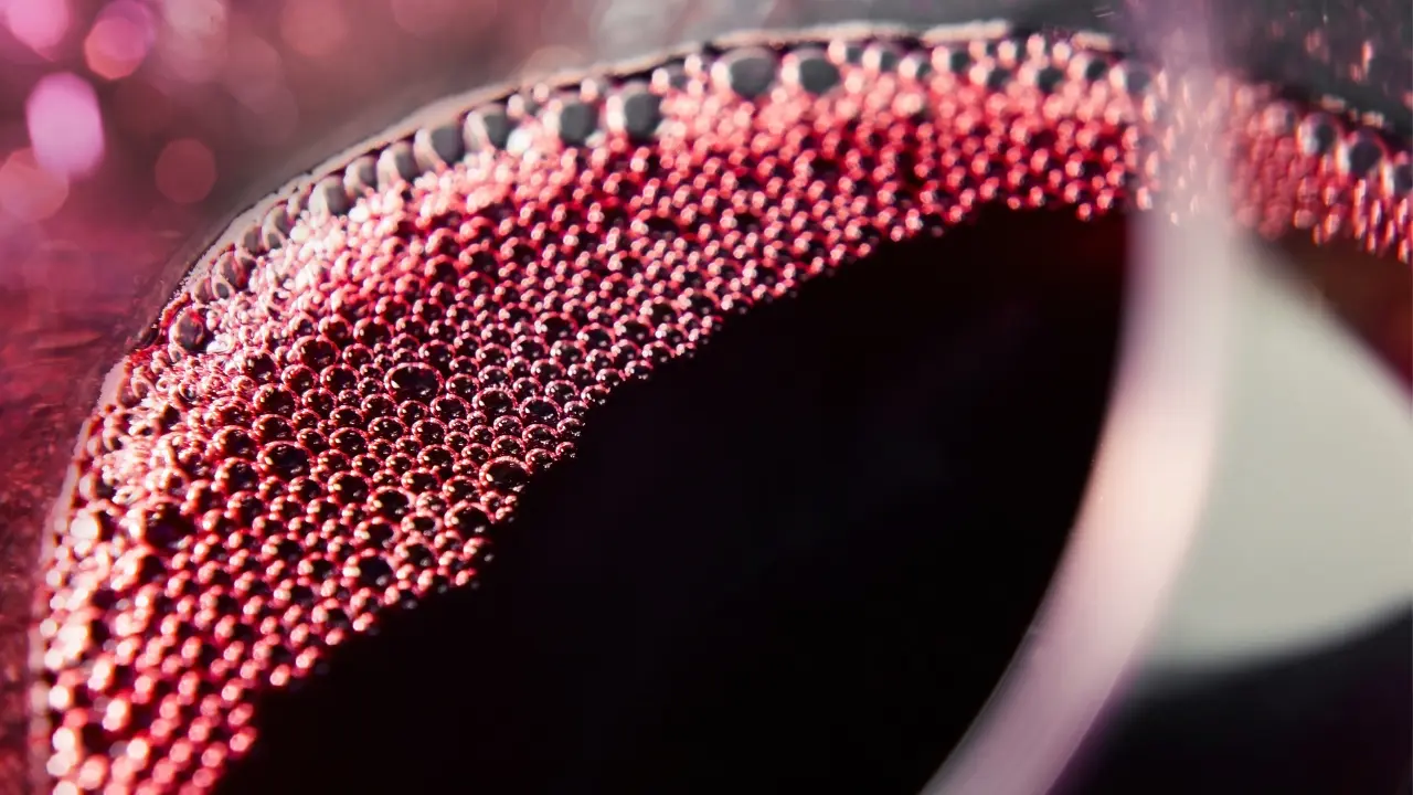 Gros plan d'un verre de vin rouge, illustrant l'expérience sensorielle du 5ème sens du vin qui associe vin et musique.